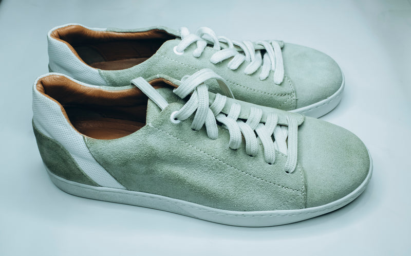Suede low-top sneakers in a light green, mint, or sage color with white laces and white rubber soles|Casual low-top sneaker.