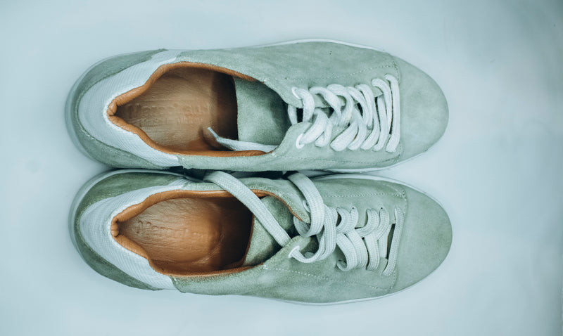 Suede low-top sneakers in a light green, mint, or sage color with white laces and white rubber soles|Casual low-top sneaker.