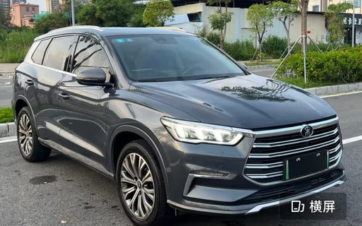 Gray SUV parked on a street with greenery in the background