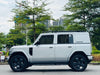 White SUV with black wheels parked on a road with trees and buildings in the background