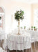 Decorative table setting with floral centerpiece in a room with large windows.