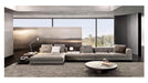 Modern living room with a large gray sectional sofa, coffee table, and decorative items.