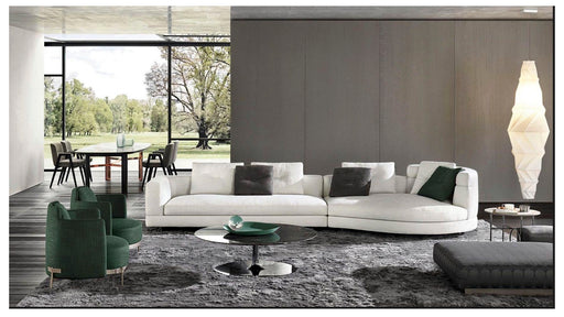 Modern living room with a white sectional sofa, green armchair, and large windows.