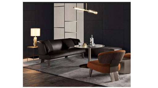 Modern living room with black leather sofa, round table, and armchair.