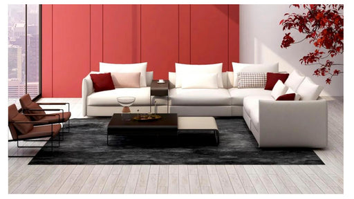 Modern living room with white sectional sofa, red accent pillows, and a coffee table.